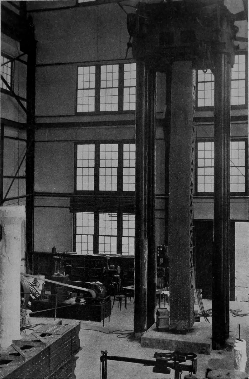 A large steel bridge column standing in a testing machine in a laboratory hall, 1918